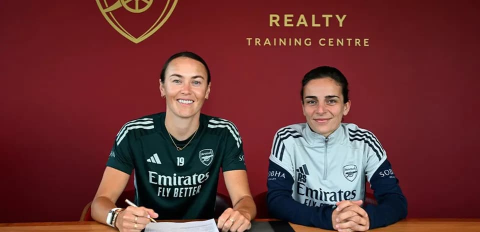 İki futbolçu müqavilə imzalayarkən masada oturub