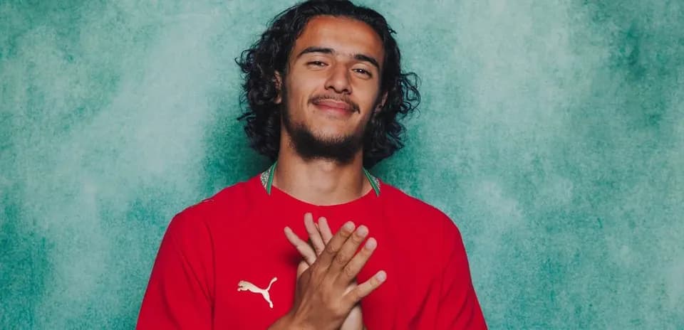 Futbolçu qırmızı forma ilə poz verir