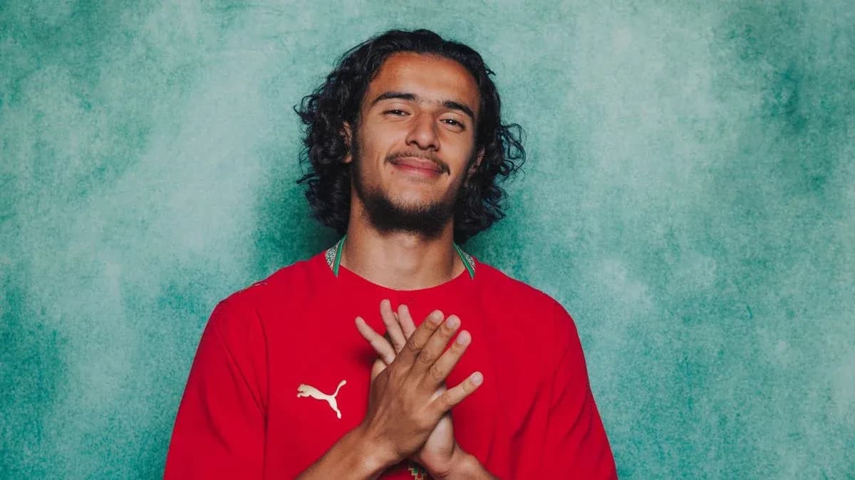 Futbolçu qırmızı forma ilə poz verir