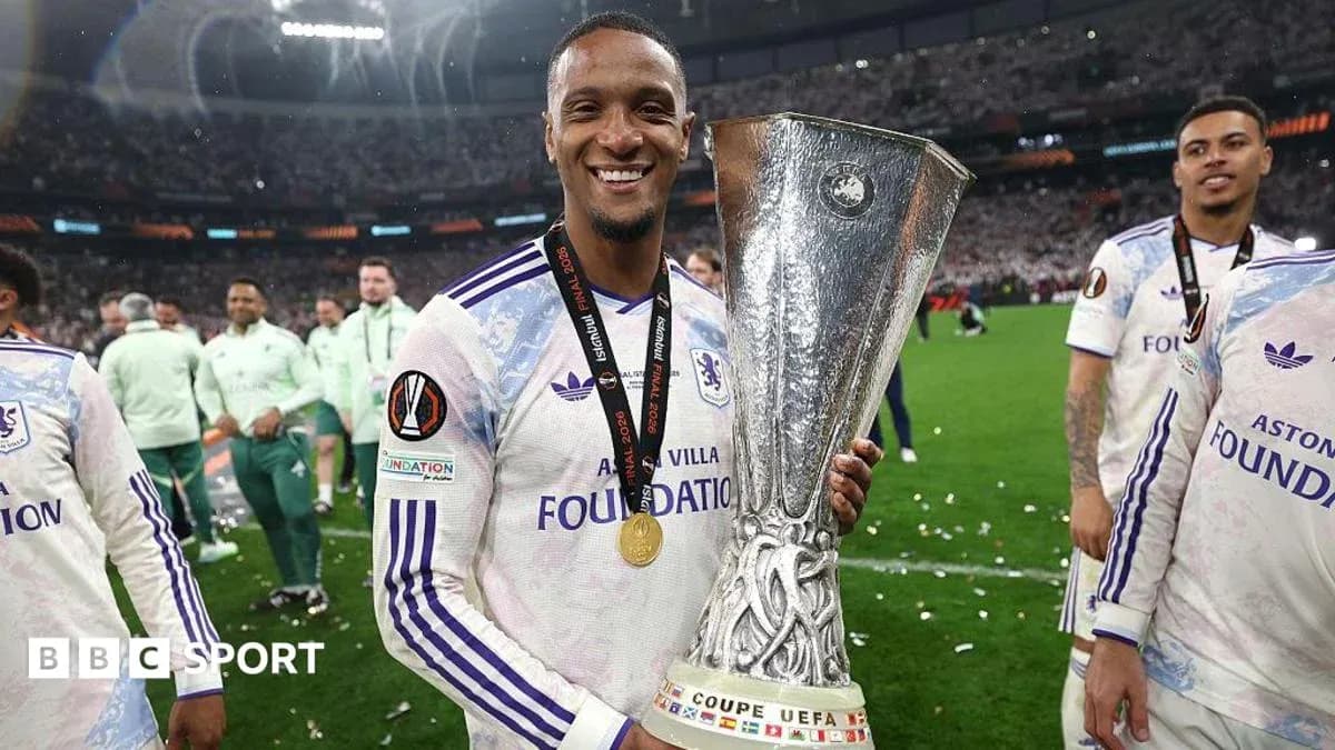 Futbolçu UEFA kubokunu qaldıraraq gülümsəyir
