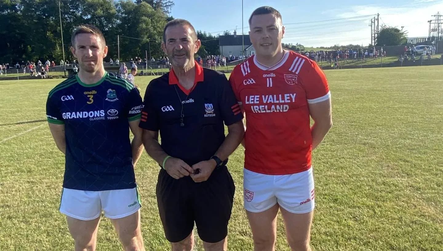 Two players and referee posing on field
