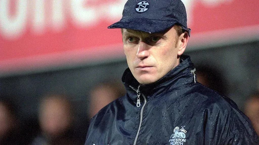 Football manager in rain jacket and cap during match
