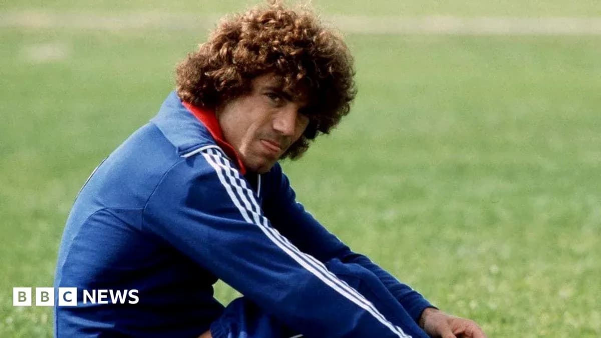 Football player sitting on grass, wearing blue tracksuit