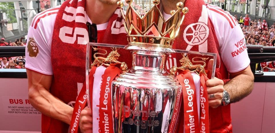 İki futbolçu Premier League kubokunu tutaraq gülümsəyir