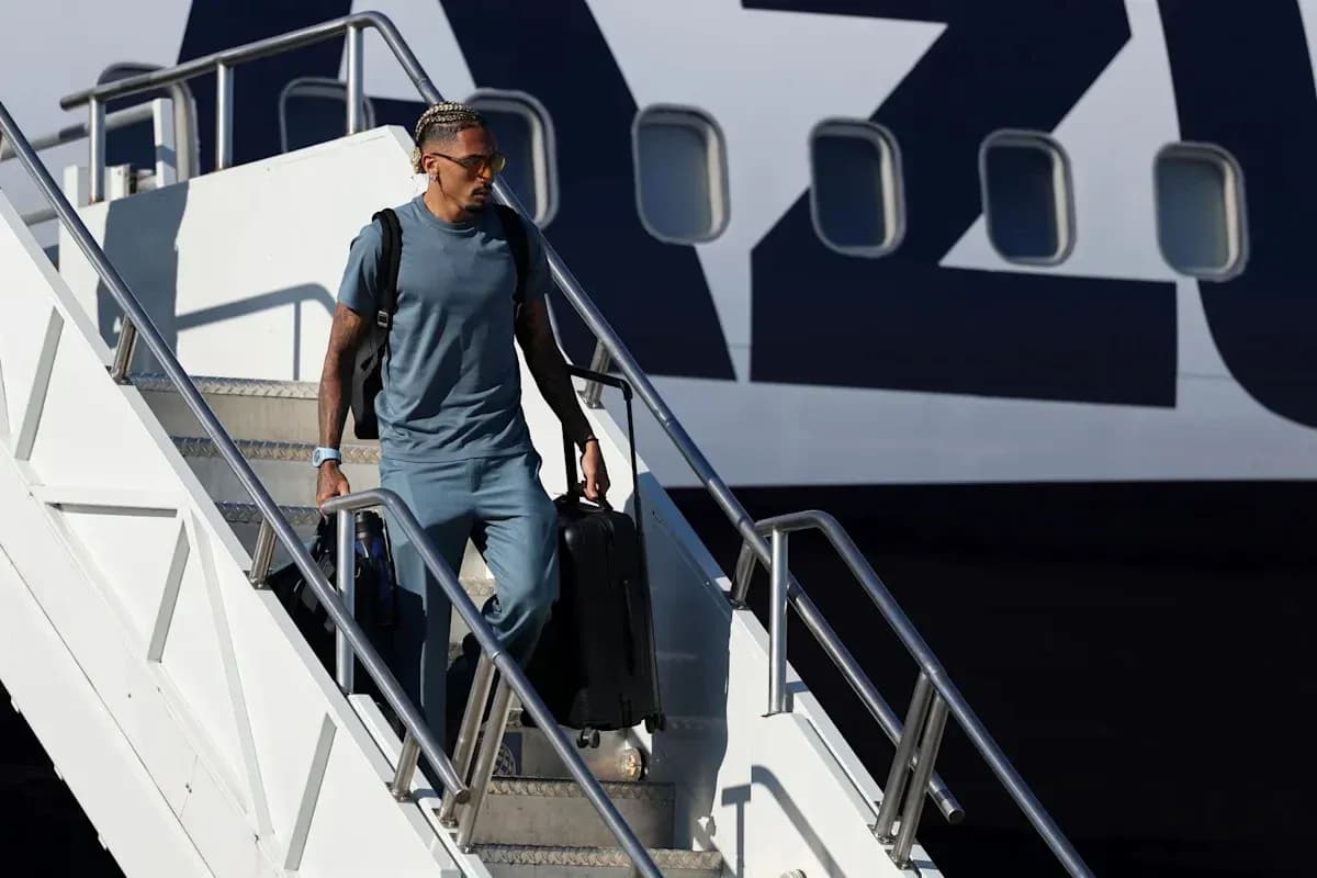 Player disembarking from airplane with suitcase