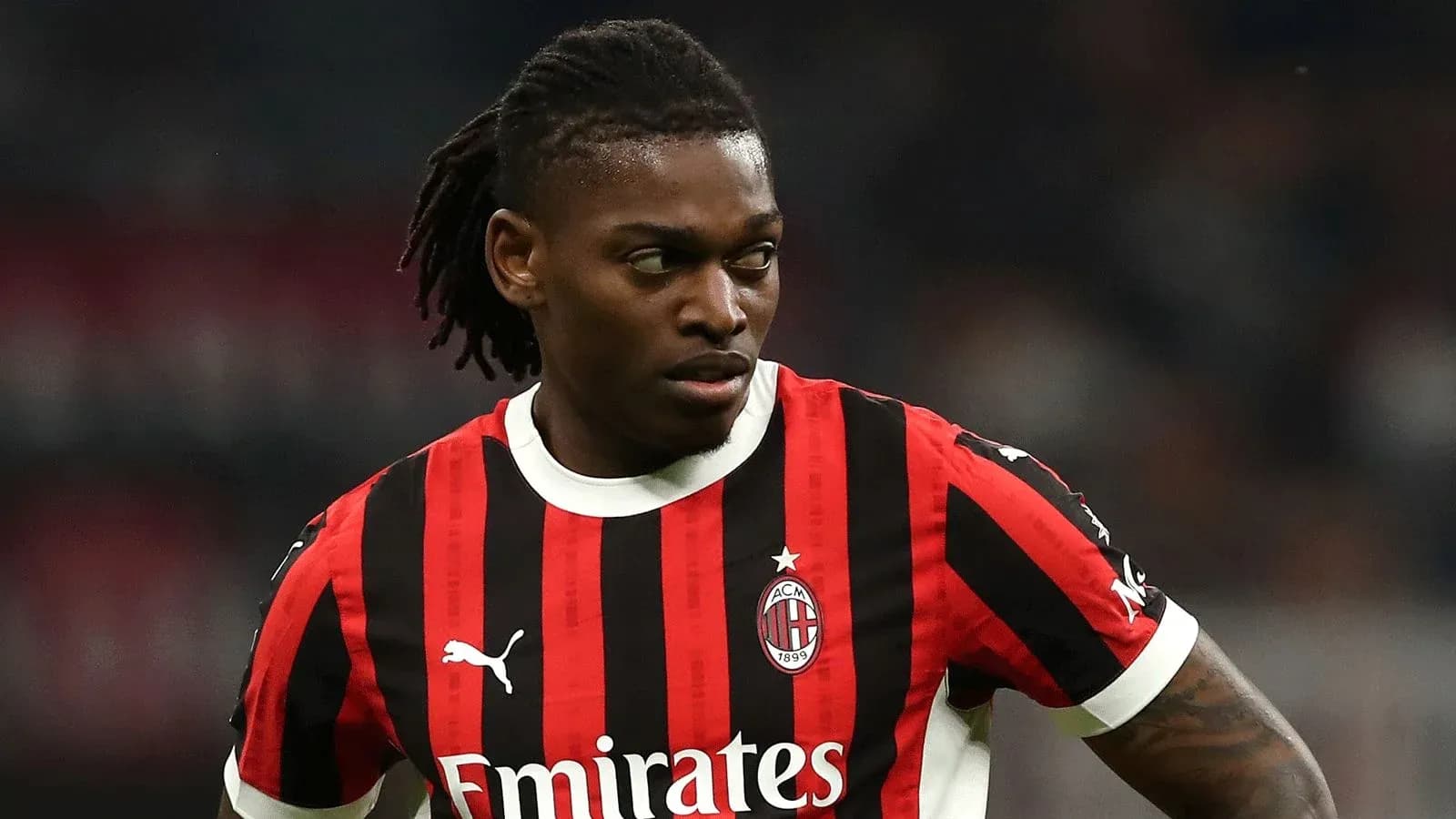 AC Milan player in red and black jersey on field