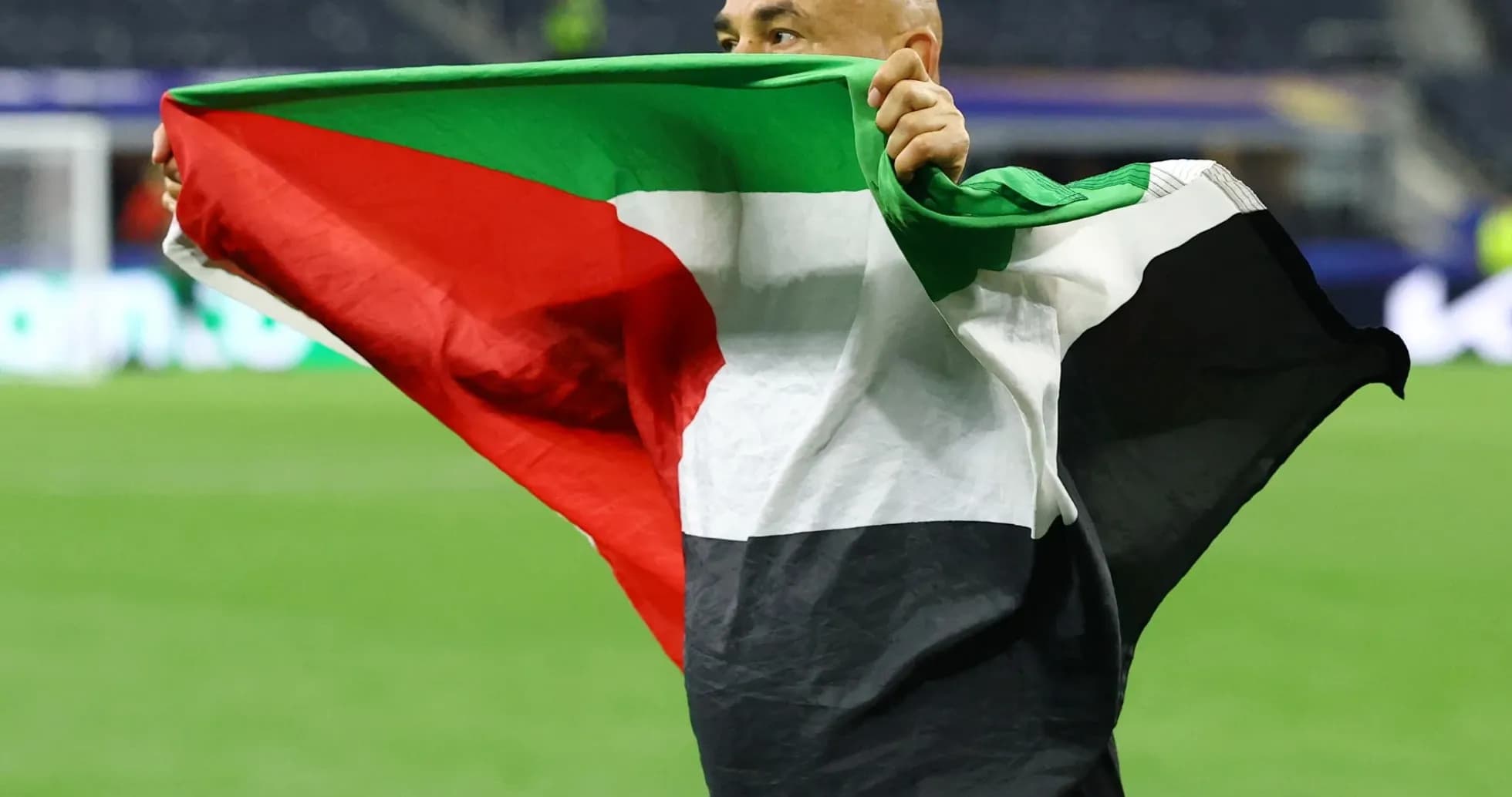 Şəxs bayrağı havada tutaraq stadionda dayanır