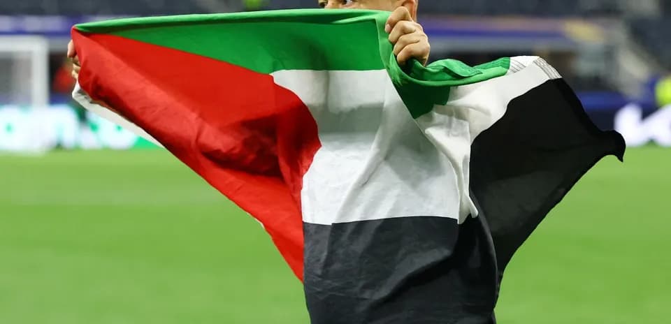 Şəxs bayrağı havada tutaraq stadionda dayanır