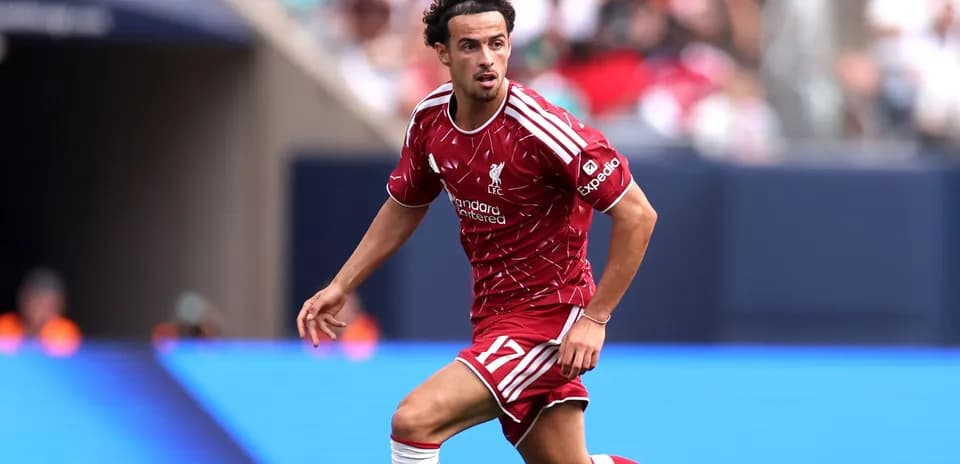 Futbolçu Liverpool formasında topa doğru irəliləyir