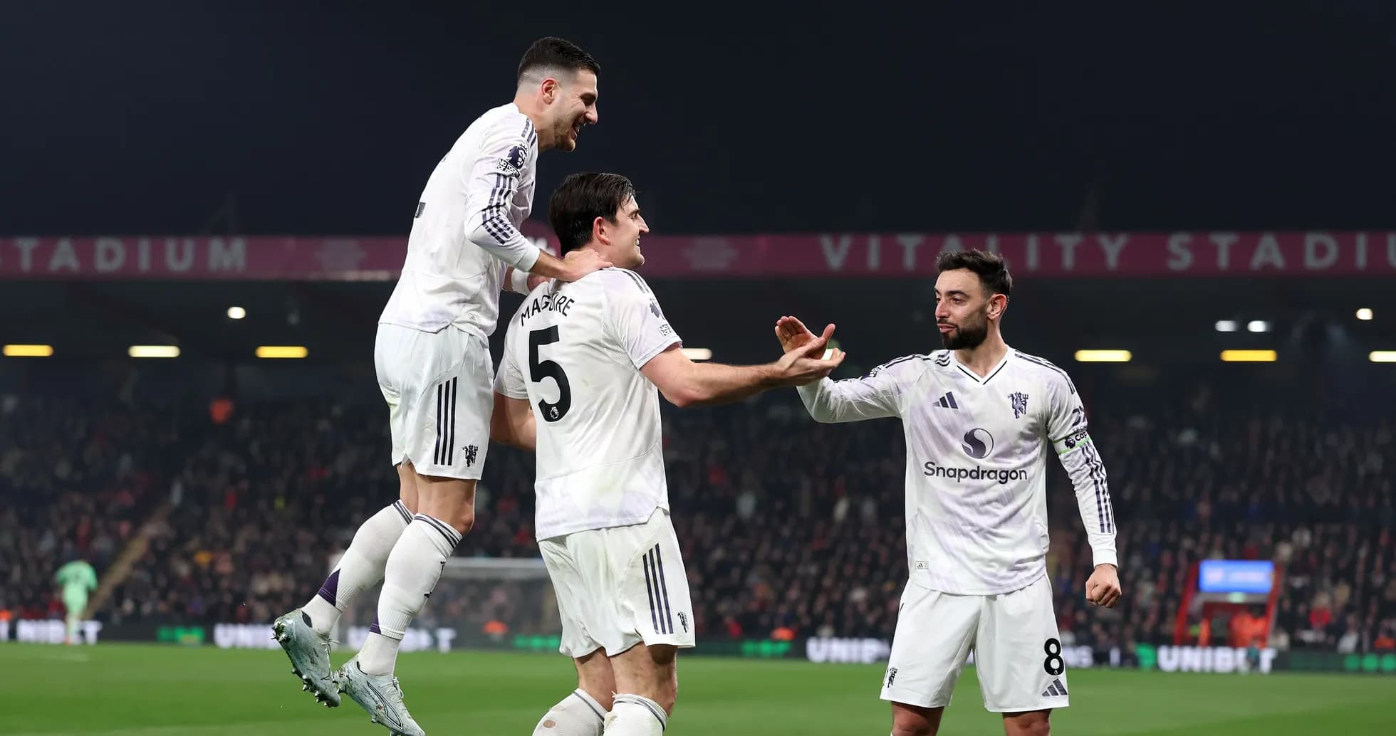 Three players celebrating a goal at stadium
