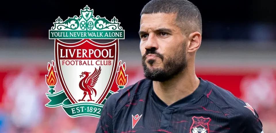 Futbolçu Liverpool logosu ilə arxa planda durur