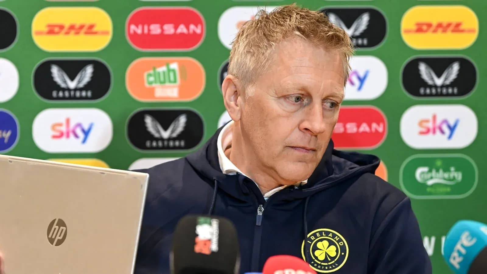 Men's football manager at press conference with laptop