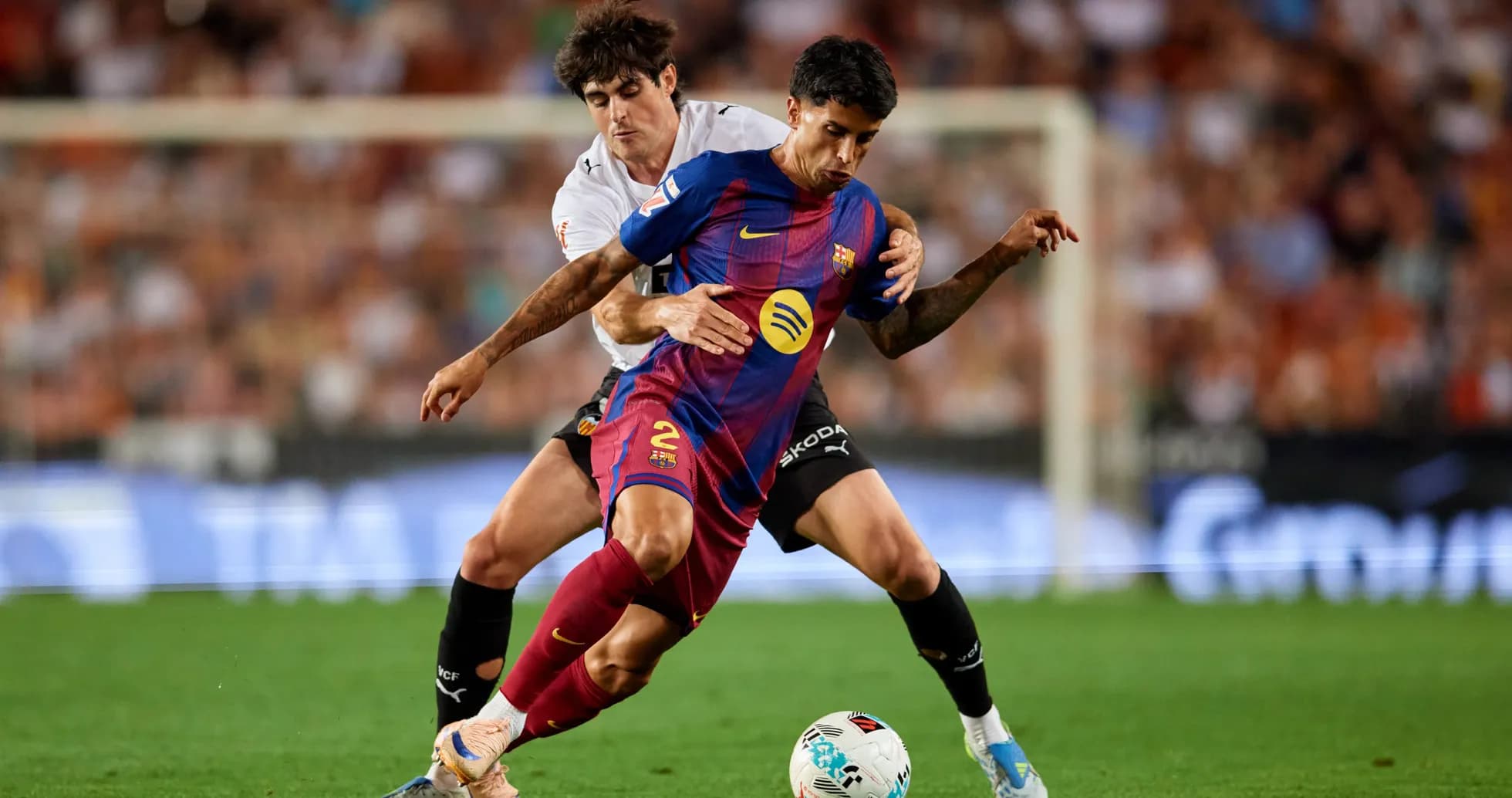 Barcelona player challenged by Valencia defender during match