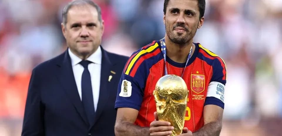 Futbolçu Dünya Kubokunu qaldırır, arxada kişi var