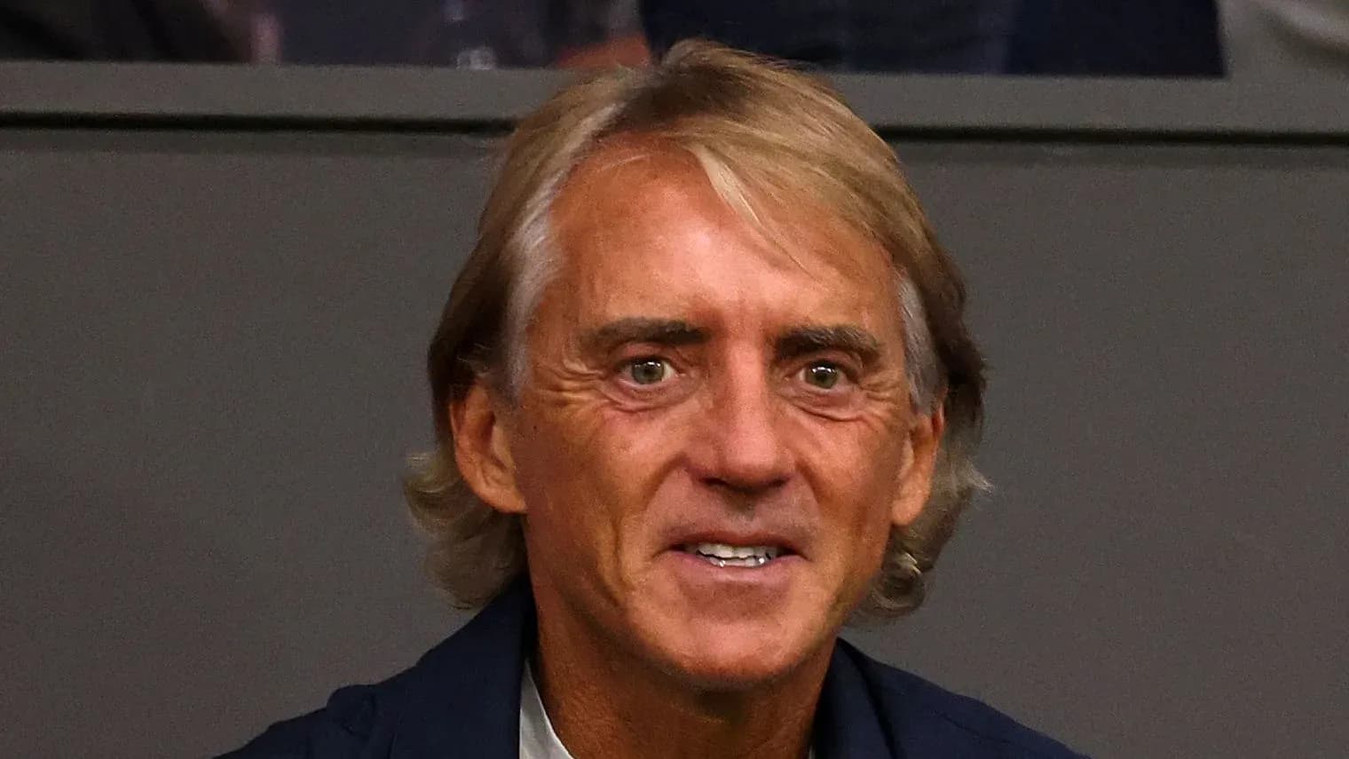 Coach smiling while watching the match from stands