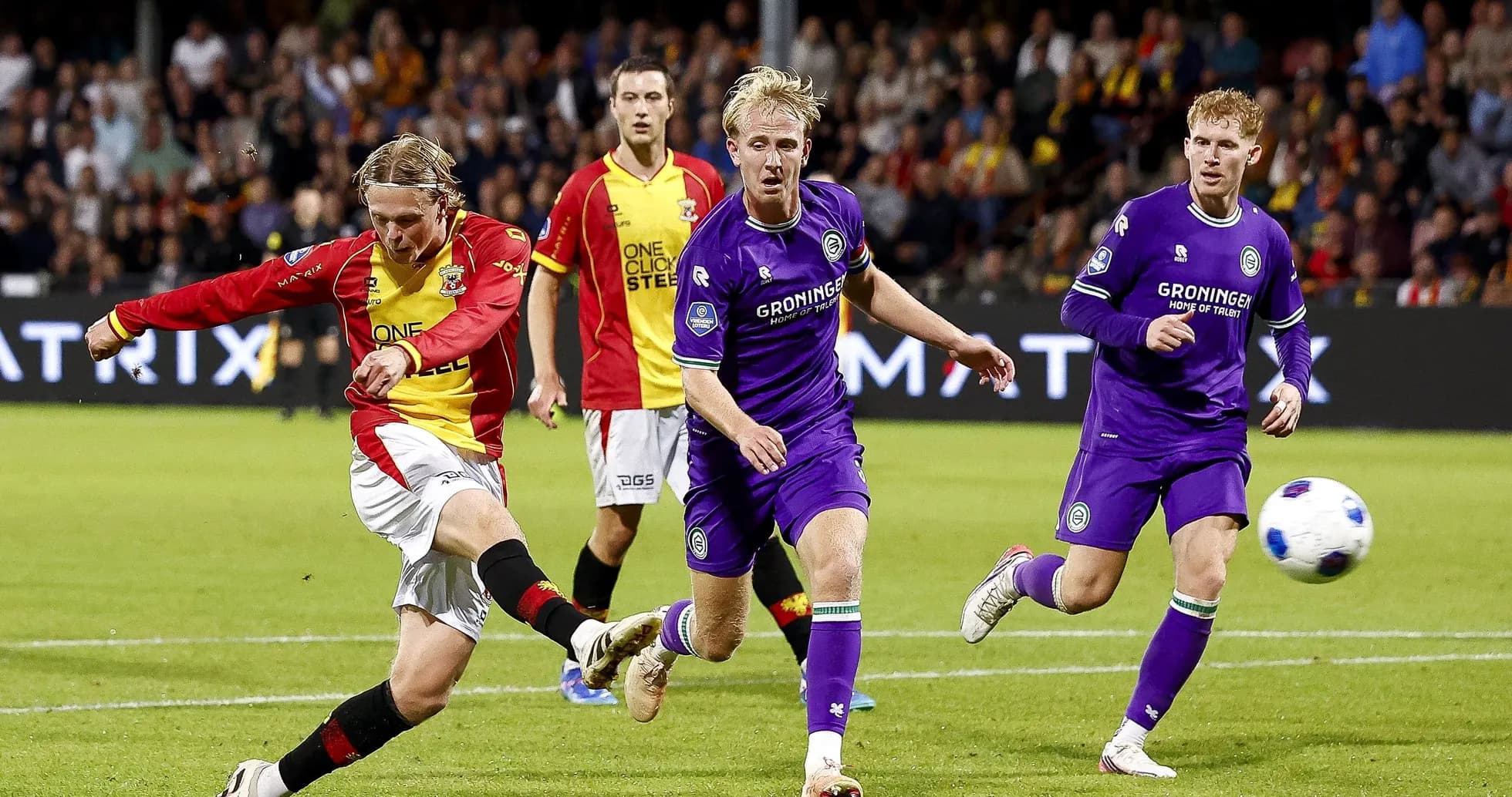 Player kicking ball with defenders nearby during match