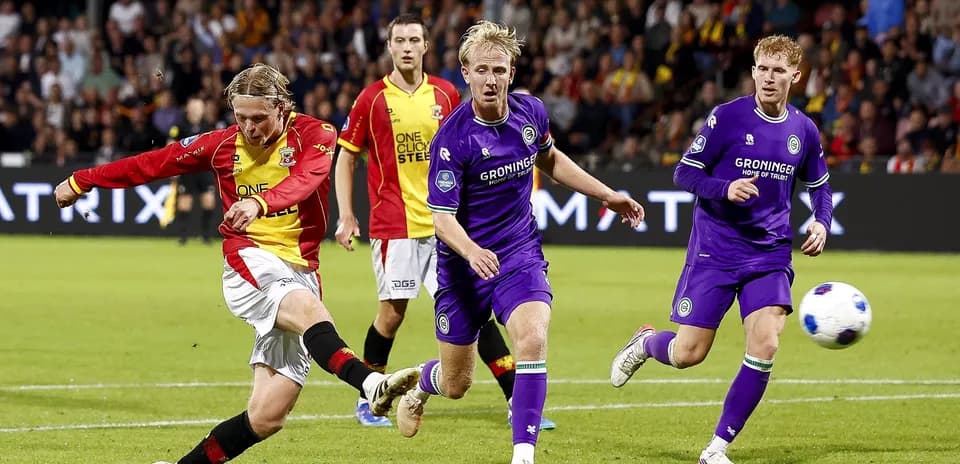 Player kicking ball with defenders nearby during match