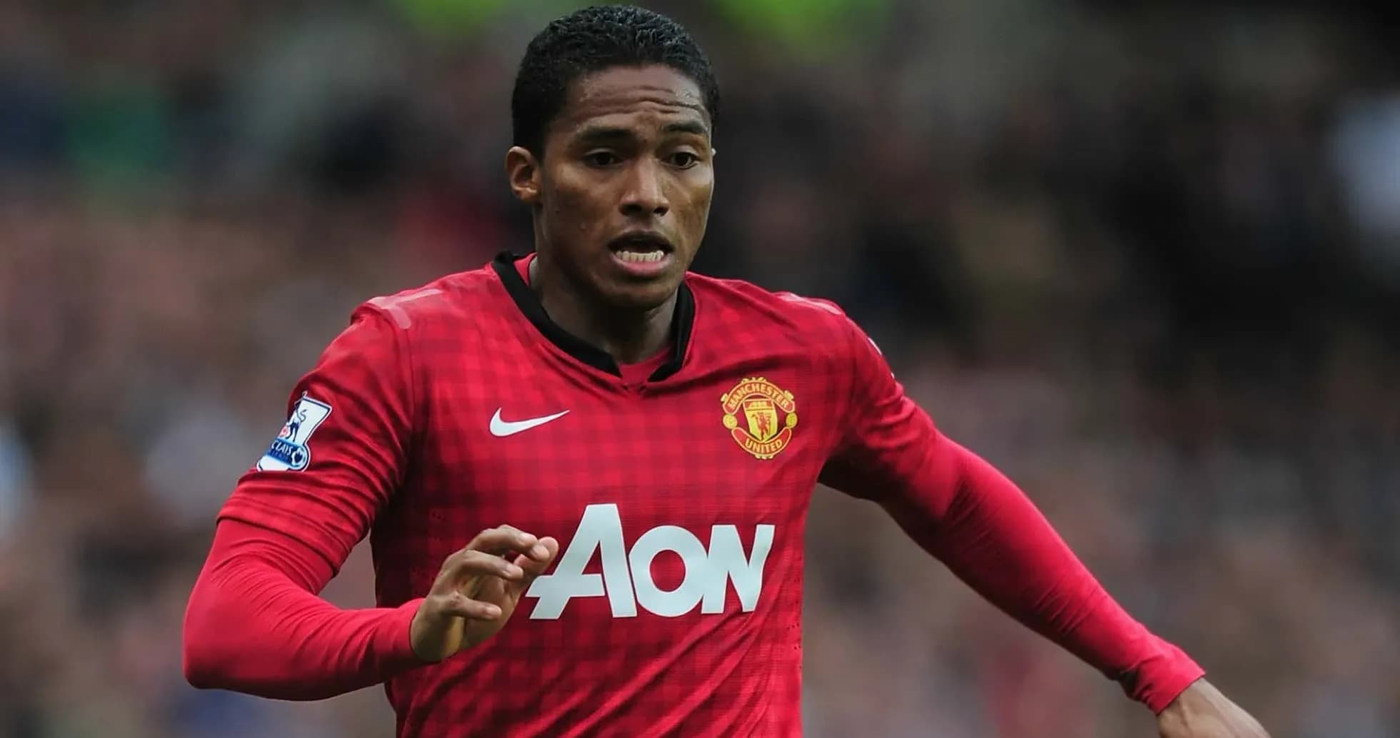 Futbolçu Manchester United formasında topa doğru qaçır