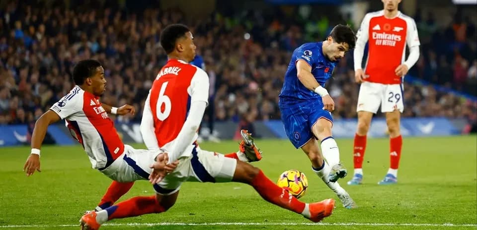 Chelsea player attempting to score against Arsenal defenders