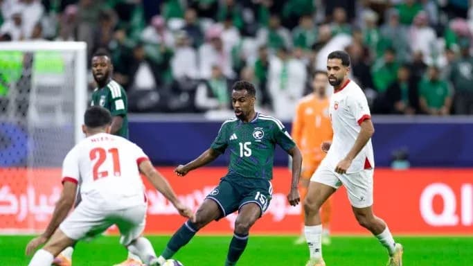 Saudi player dribbling past two opponents during match