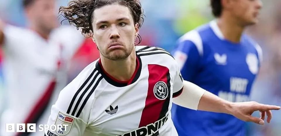 Futbolçu qolu qeyd edir, arxa planda rəqib var