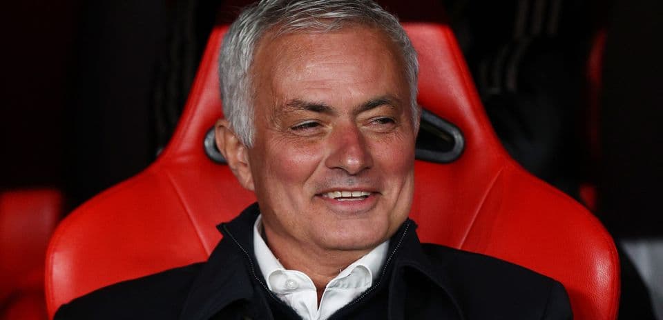 Football manager seated on red bench during match