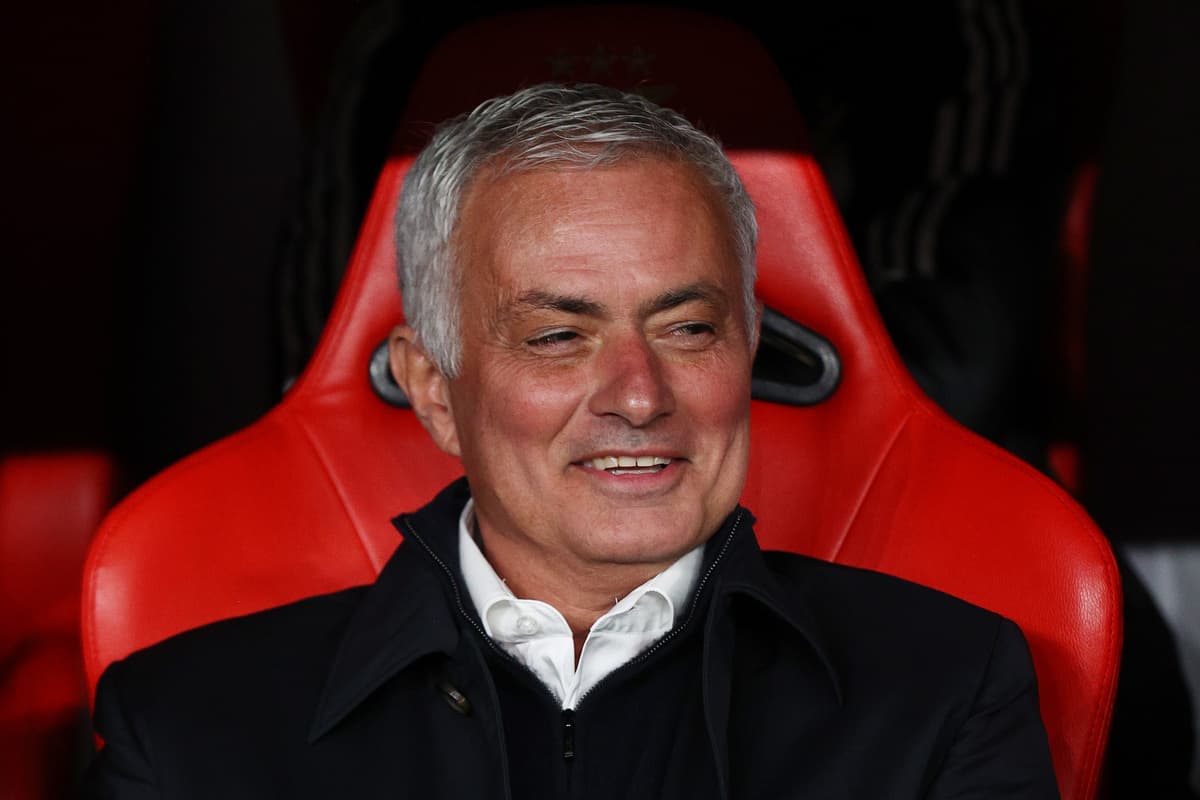 Football manager seated on red bench during match