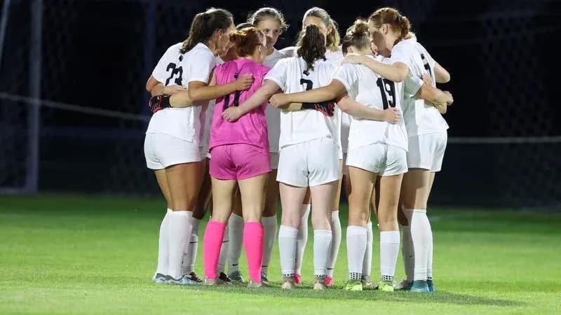 Women's soccer team huddled together on field