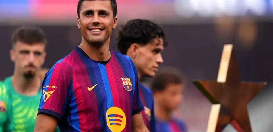 Futbolçu mükafatla podiumda gülərək dayanır