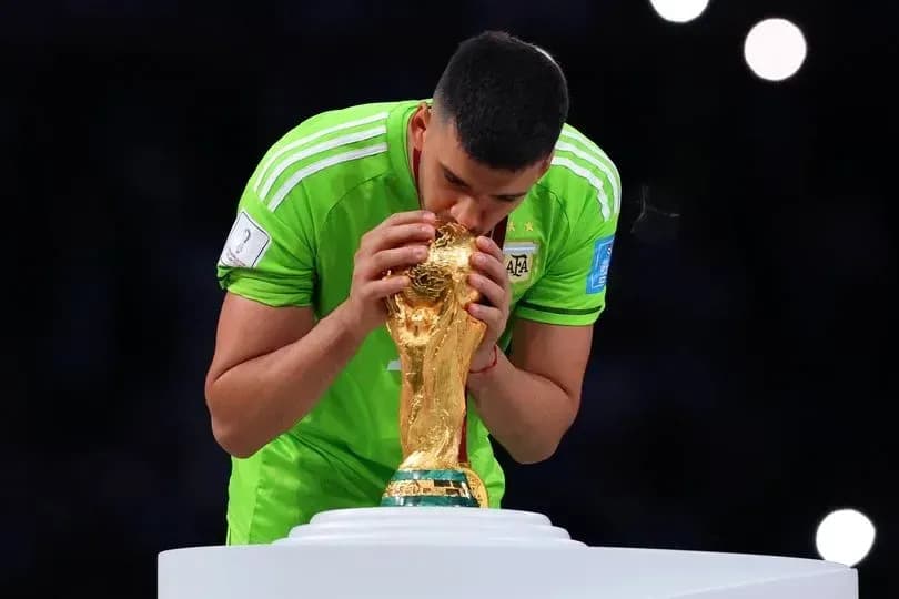 Goalkeeper kissing FIFA World Cup trophy on podium