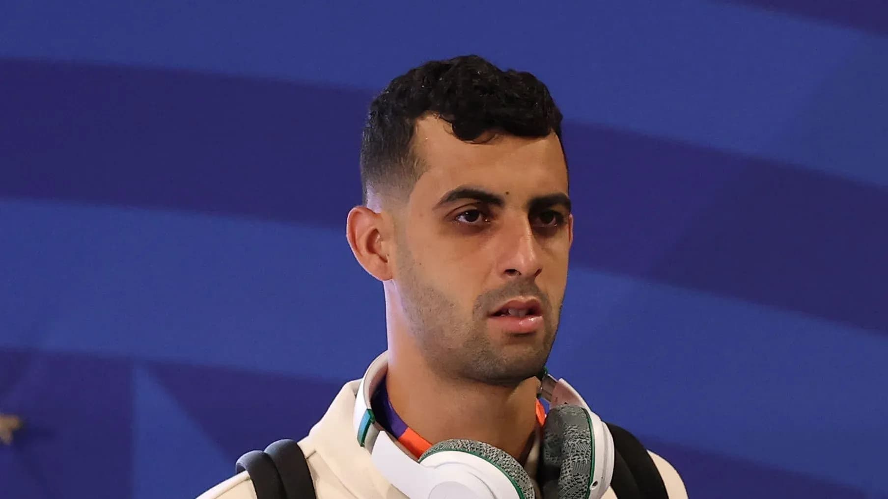 Futbolçu mavi fonda musiqi qulaqlığı ilə