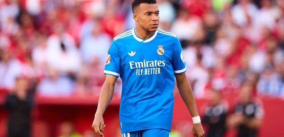 Futbolçu mavi forma ilə meydanda yürüyür