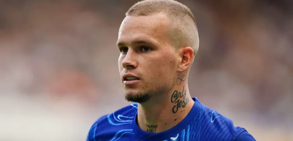 Futbolçu mavi forma ilə meydanda durur