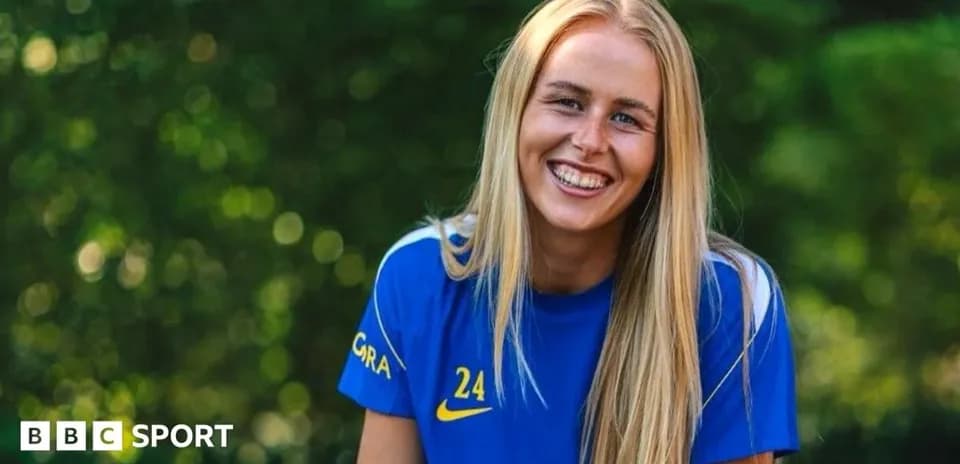 Futbolçu gülümsəyərək mavi forma geyinib
