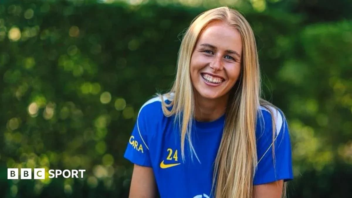 Futbolçu gülümsəyərək mavi forma geyinib