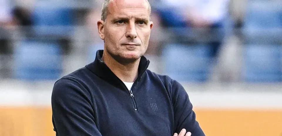 Football coach with arms crossed observing match
