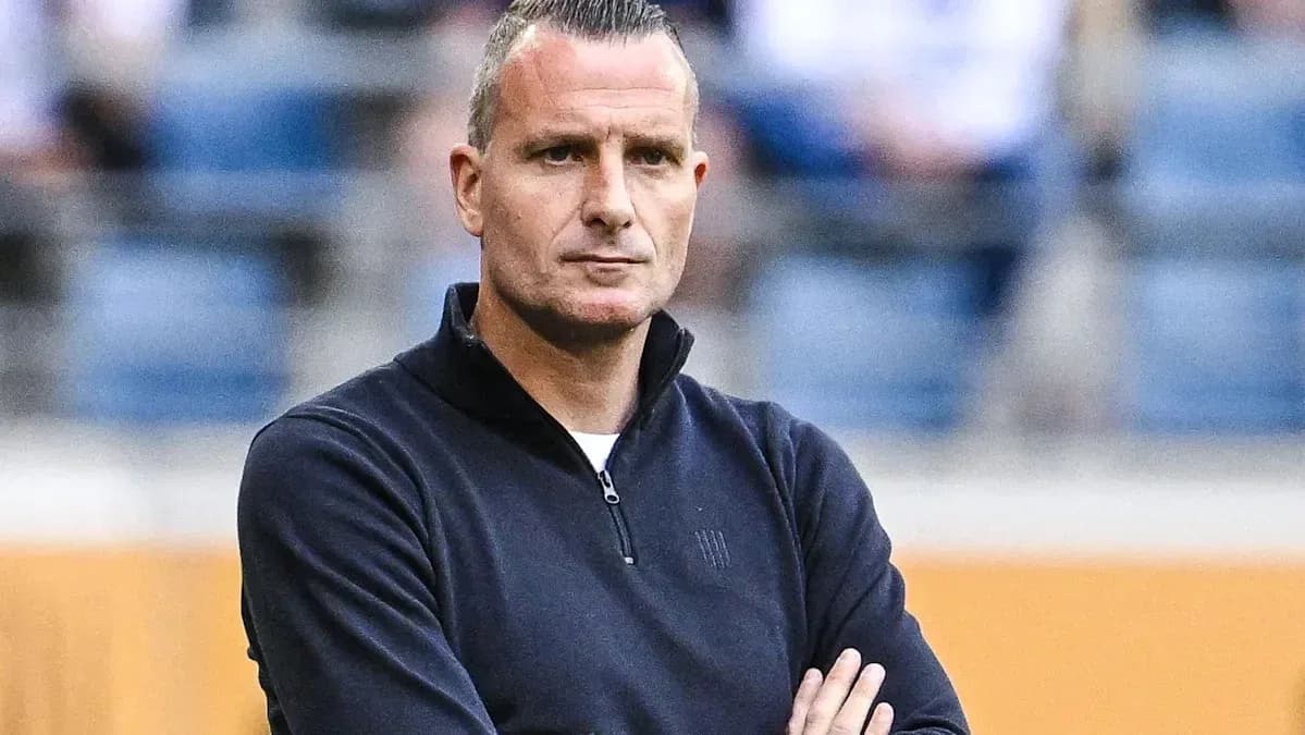 Football coach with arms crossed observing match