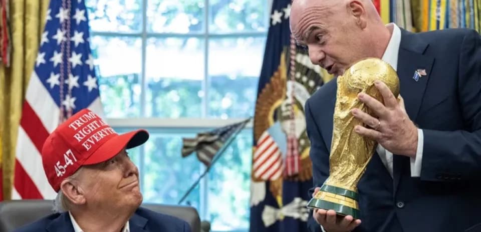 Two men discussing FIFA World Cup trophy in office