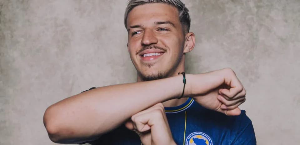 Futbolçu mavi forma ilə gülümsəyir