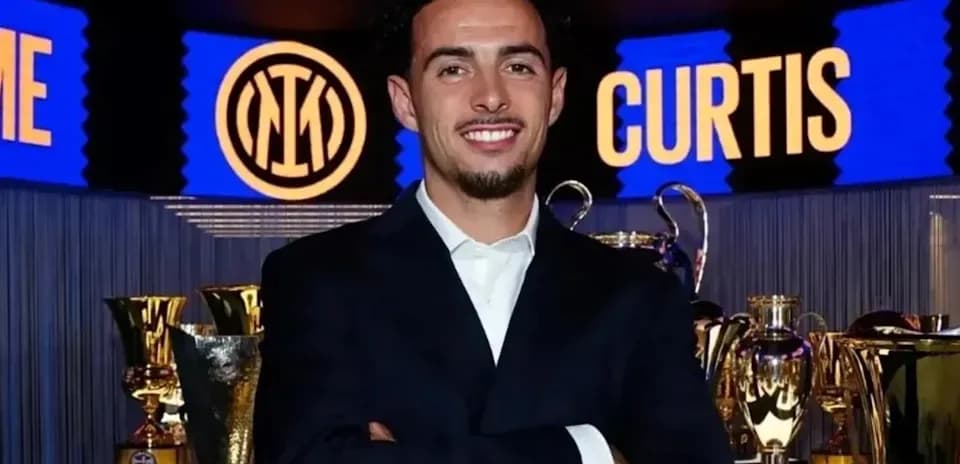 Young man in suit smiling near trophies