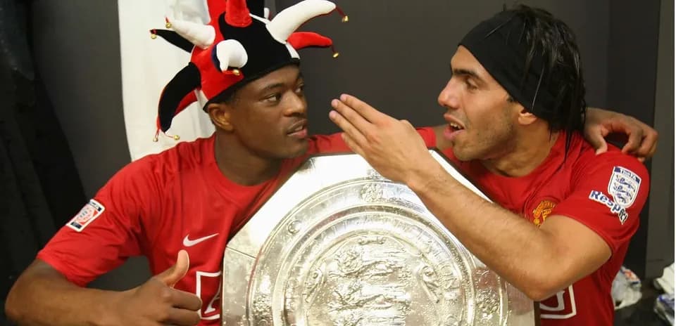 Two players celebrating with a trophy in locker room