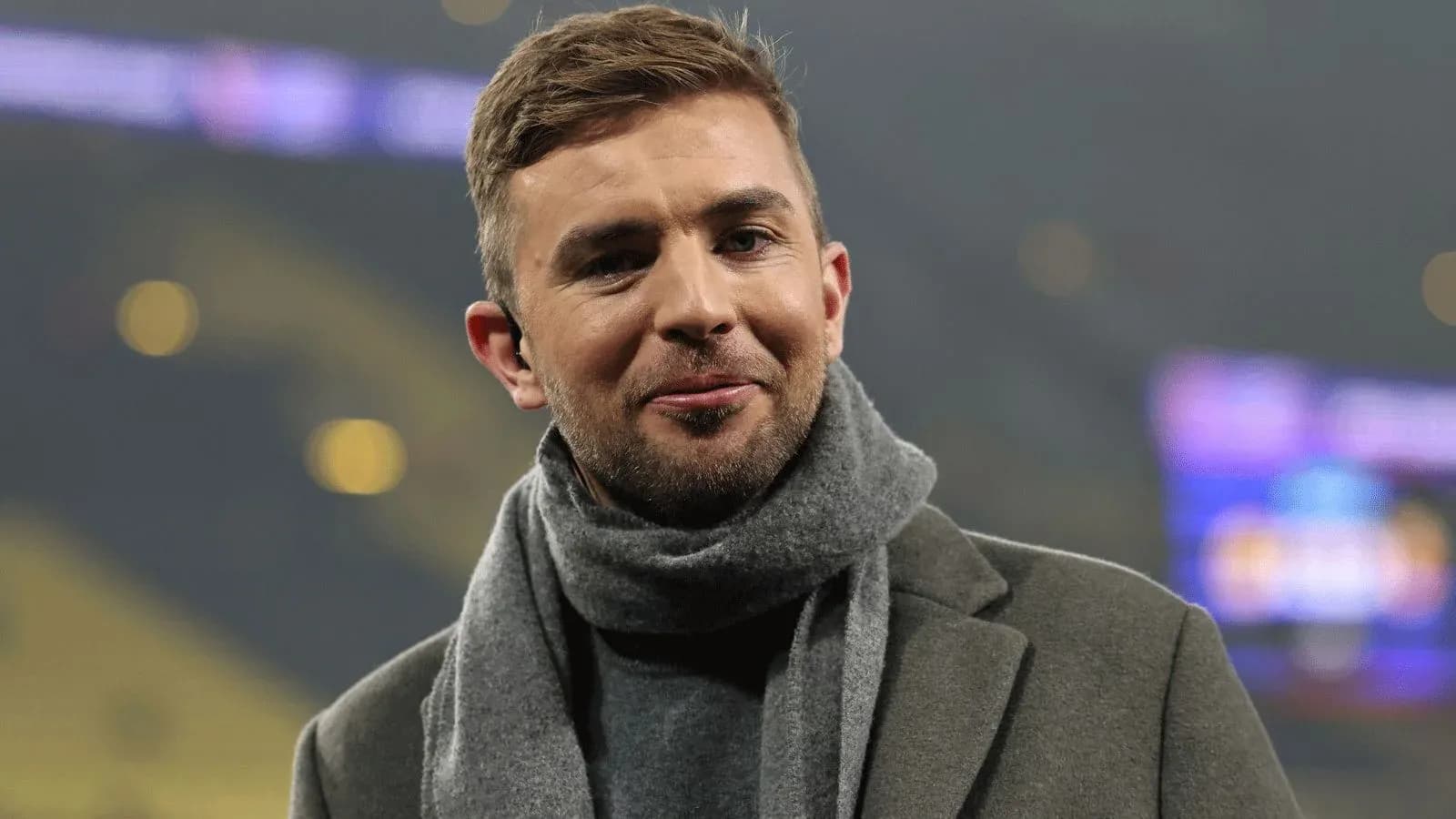 Man in a coat and scarf smiling at event