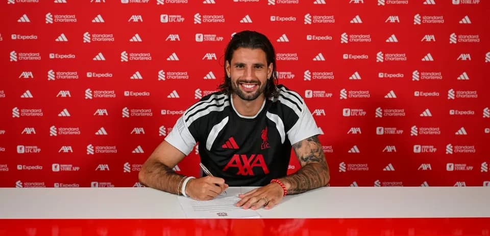 Futbolçu müqavilə imzalayarkən masada oturub