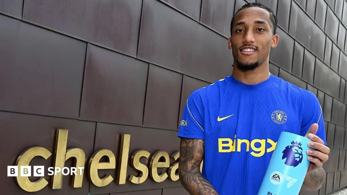 Futbolçu Chelsea loqosunun yanında mükafat tutur