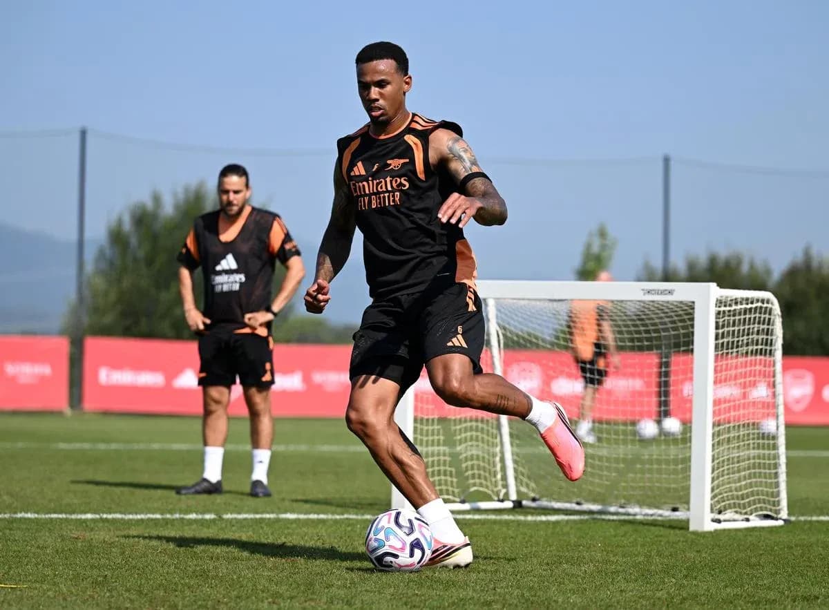 Futbolçu top ilə məşq edir, arxa planda komanda yoldaşları var