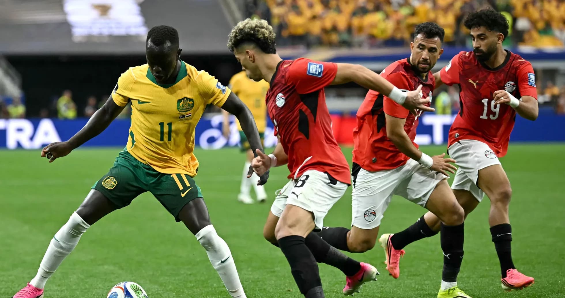Australian player dribbling past Egyptian defenders during match