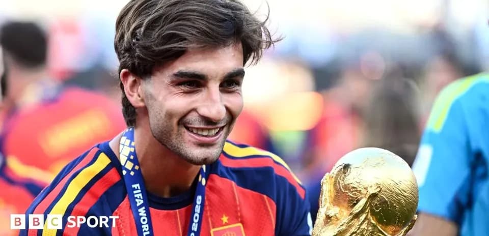 Futbolçu FIFA Dünya Kubokunu tutaraq gülümsəyir