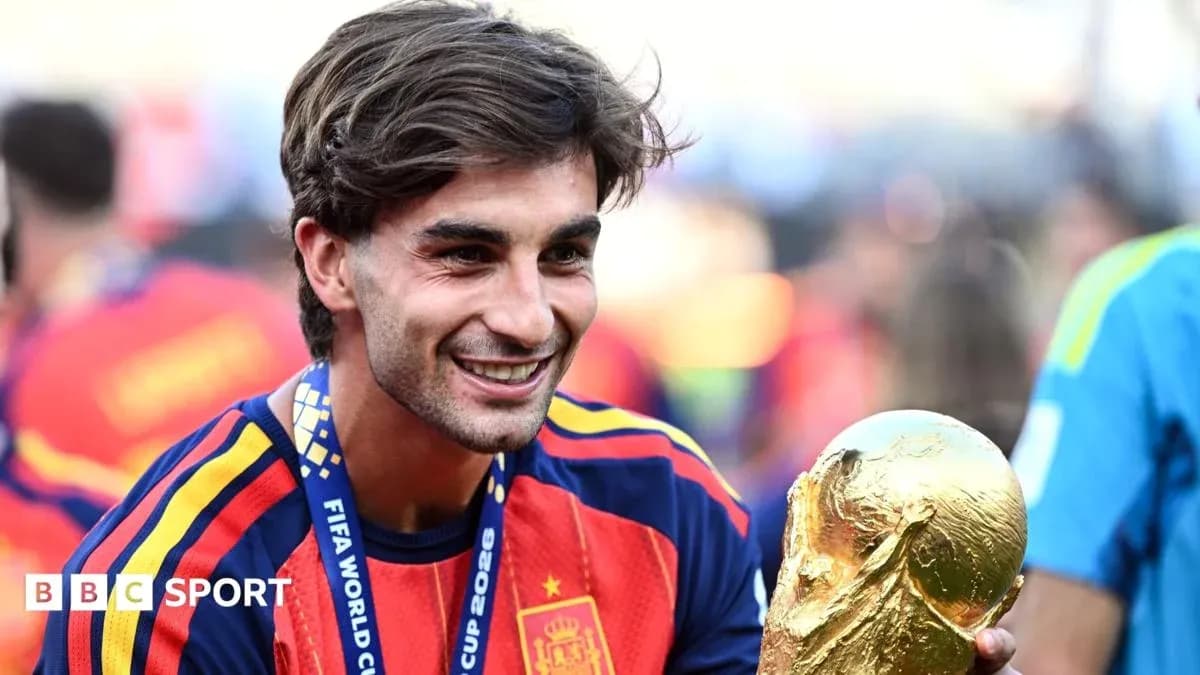Futbolçu FIFA Dünya Kubokunu tutaraq gülümsəyir