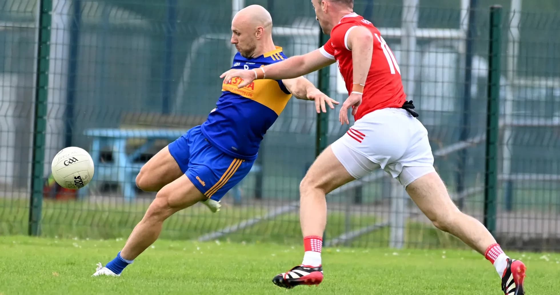 Player kicking ball while being challenged by opponent