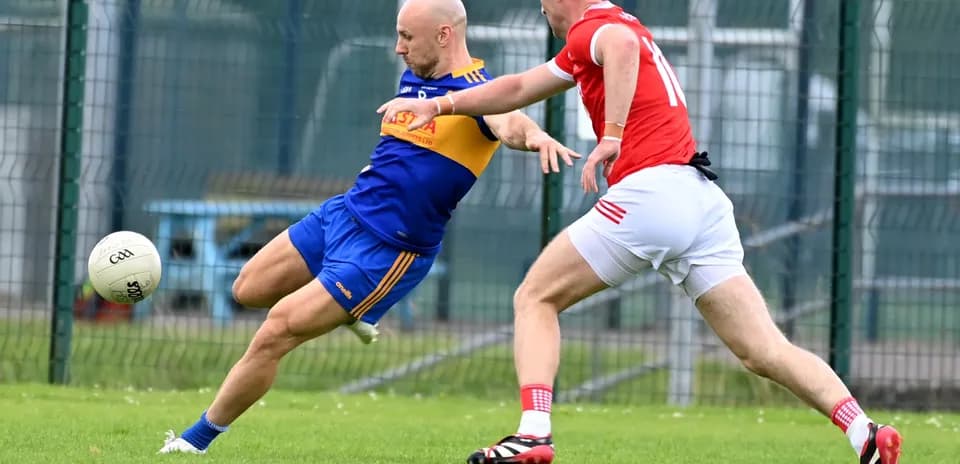 Player kicking ball while being challenged by opponent